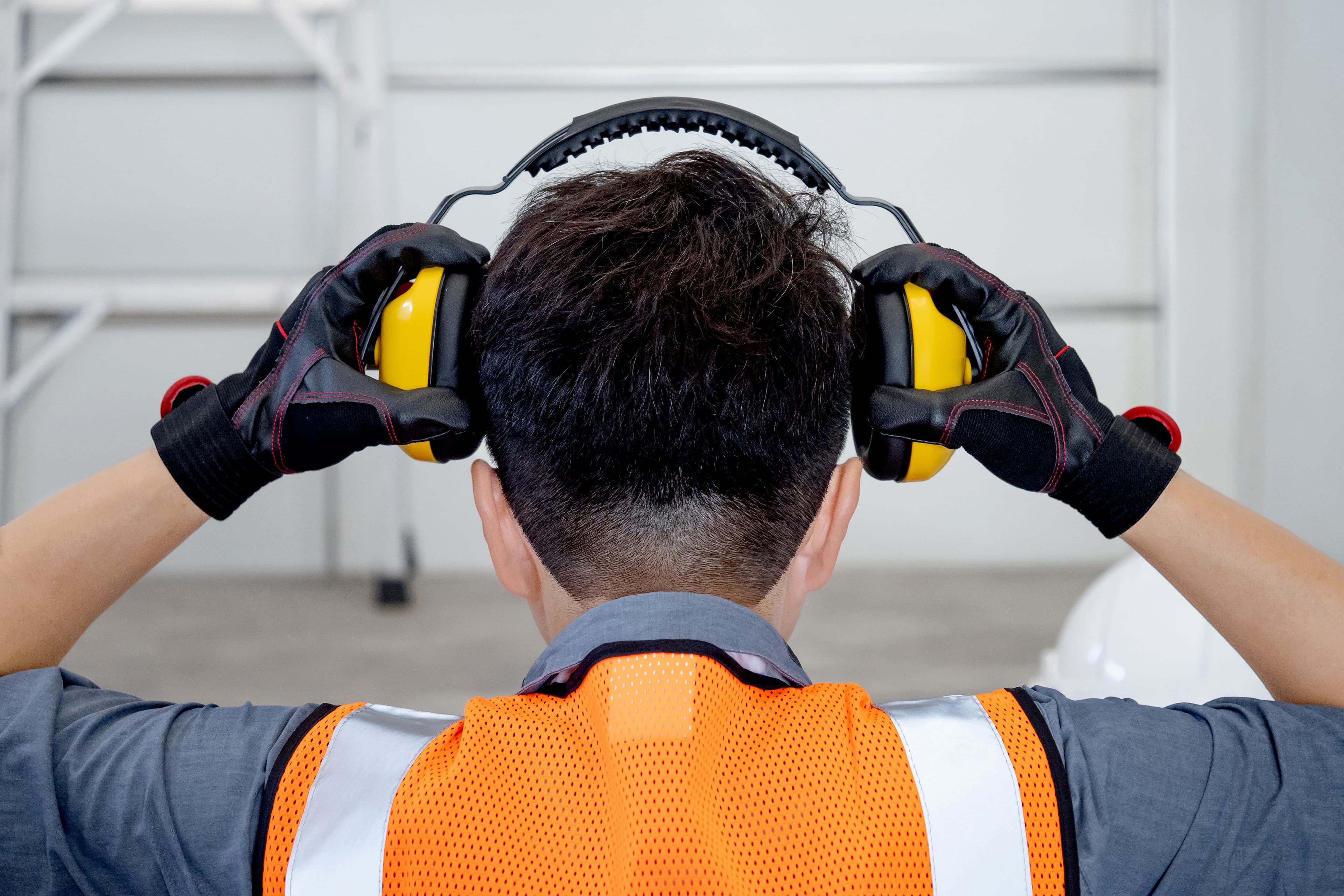 industrial worker putting ear muffs on